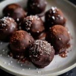 Plate of rich chocolate brownie balls dusted with sea salt and cocoa powder